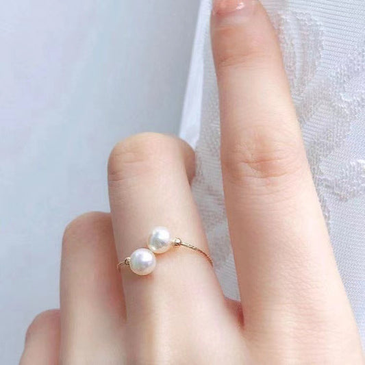 Bague Elastique Or 18K avec deux perles blanches élégantes portée sur un doigt