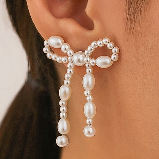 Boucles d'oreilles chic Moyyudé en perles blanches formant un nœud élégant porté à l'oreille