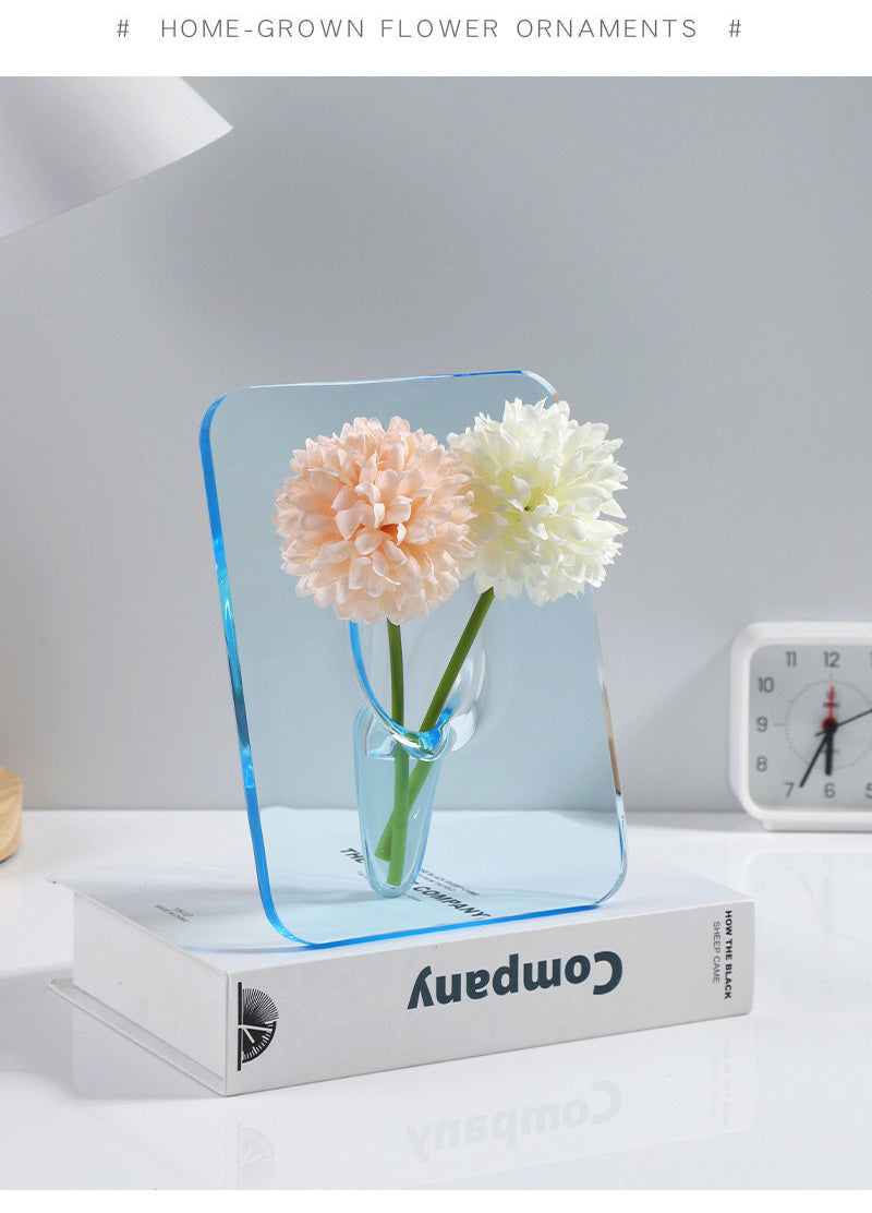 Vase acrylique transparent Moyyude avec fleurs décoratives posé sur un livre blanc moderne