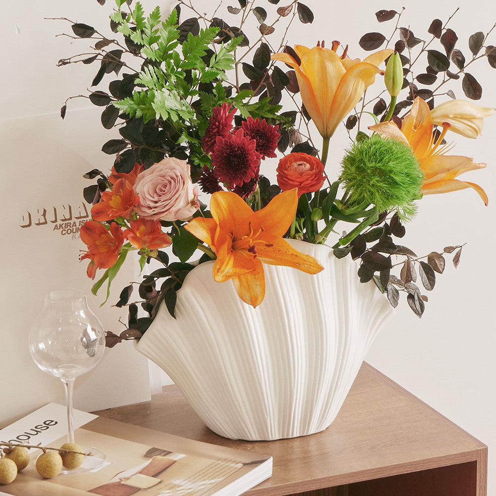 Vase En Céramique Fait Main blanc avec design ondulé rempli de fleurs colorées sur une table en bois